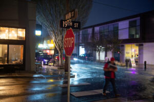 A pedestrian crosses a darkened crosswalk at the corner of 19th and Main streets in Washougal. City Councilor Molly Coston is advocating for the City of Washougal to upgrade the lighting and brighten a dark downtown. (James Rexroad/for The Columbian)
