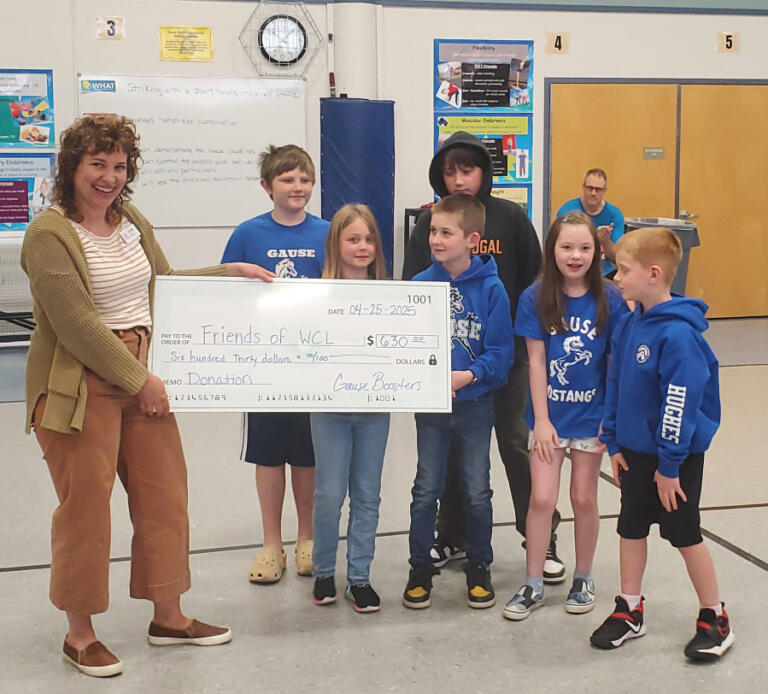 Washougal Community Library Manager Zoe Nash, left, receives a check for $630 from Gause Elementary School students during a school assembly on April 25, 2025.