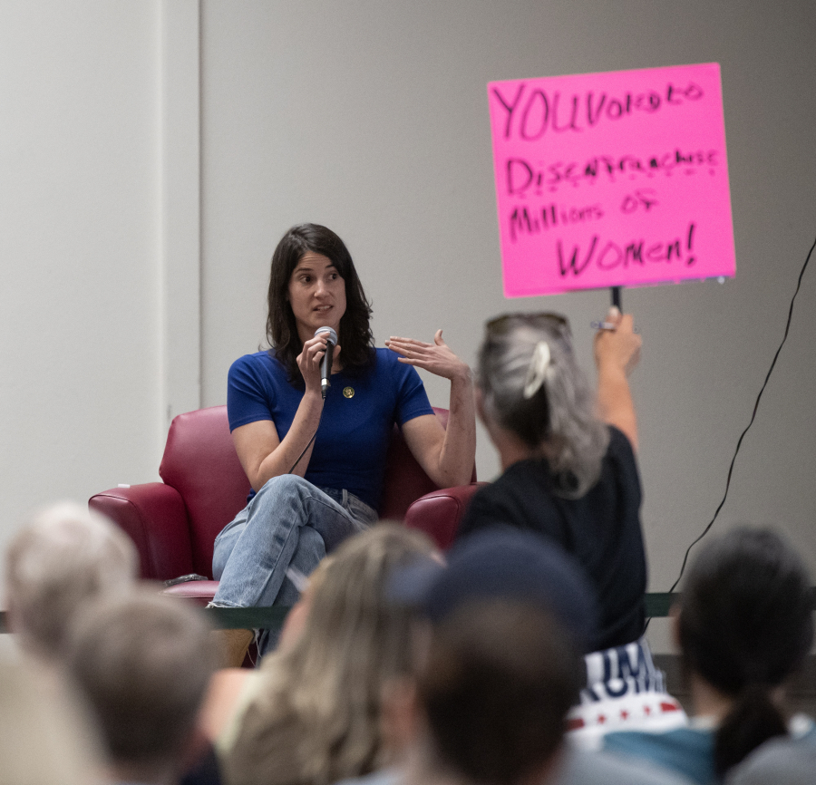 An audience member waves a sign toward US Rep. Marie Gluesenkamp-Perez (WA-03) as she leaves a town hall Thursday, April 24, 2025, at Marshall/Luepke Community Center. Hundreds of constituents lined up for the event with signs expressing their displeasure at the voting record of Perez. (Taylor Balkom/The Columbian)
