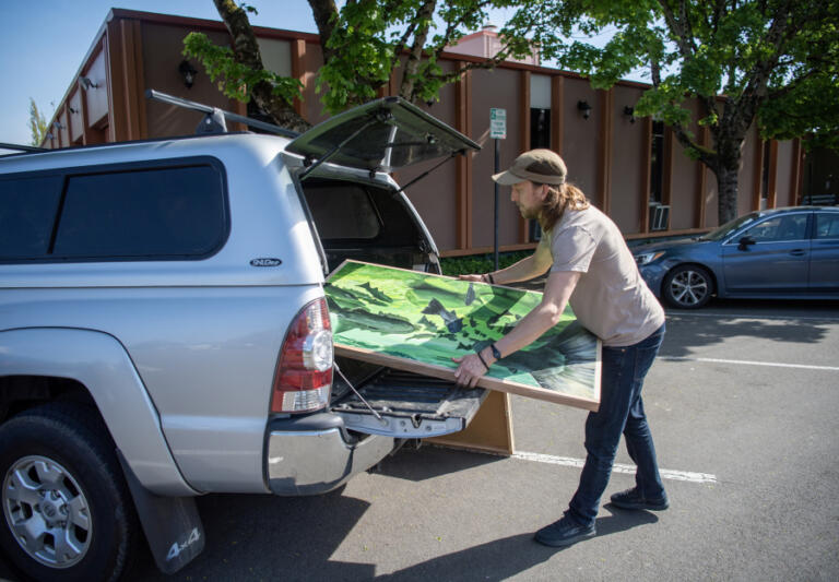 Travis London transfers one of his paintings from his car to the Camas Public Library on Friday.