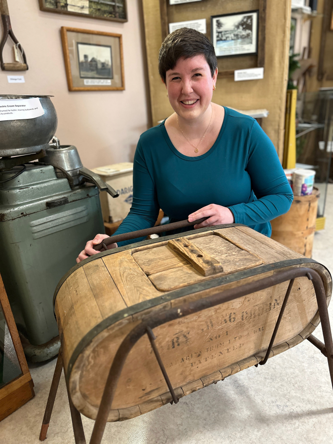 Two Rivers Heritage Museum Director Julianne Lawrence shows visitors an Oregon Trail butter churn included in the Washougal museum’s collection of historical artifacts. (Contributed by Two Rivers Heritage Museum)