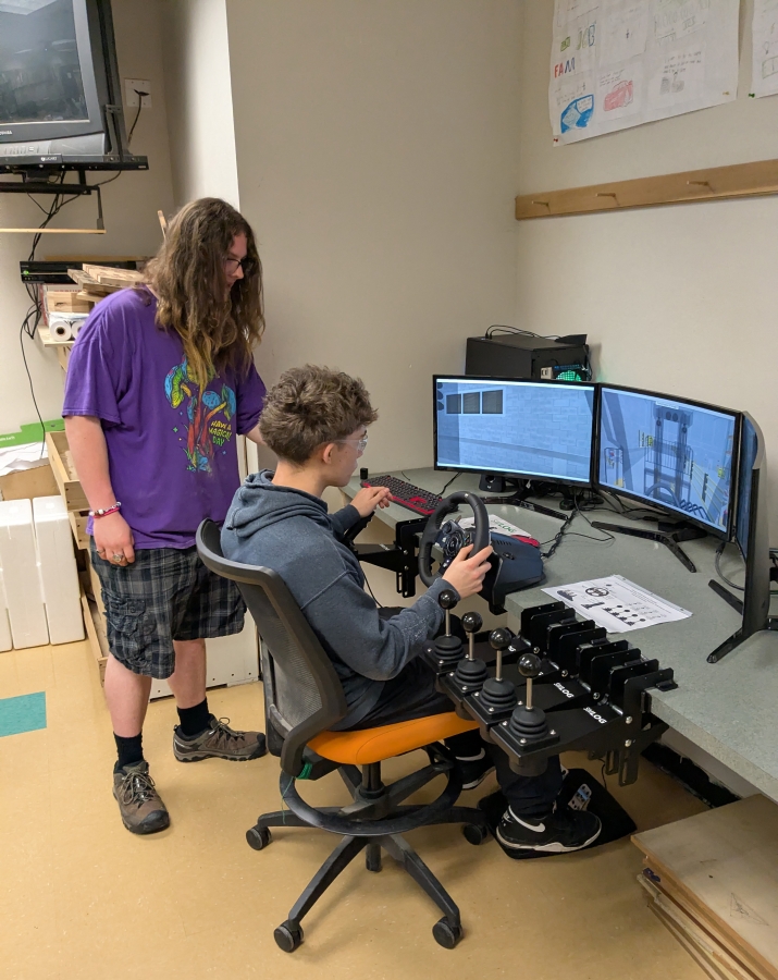 Washougal High School student Max Horton, right, uses the school’s new forklift simulator on May 22, 2025, while fellow student Jacob Dillie looks on. (Contributed by the Washougal School District)