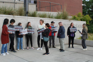 Camas students and parents worried about how the Camas School District’s recent round of budget cuts will impact the district’s music, choir and theater arts programs hold “Save Our Music, Save Our Arts” signs outside the school district’s Joyce Garver Theater on May 20. (Kelly Moyer/The Columbian)