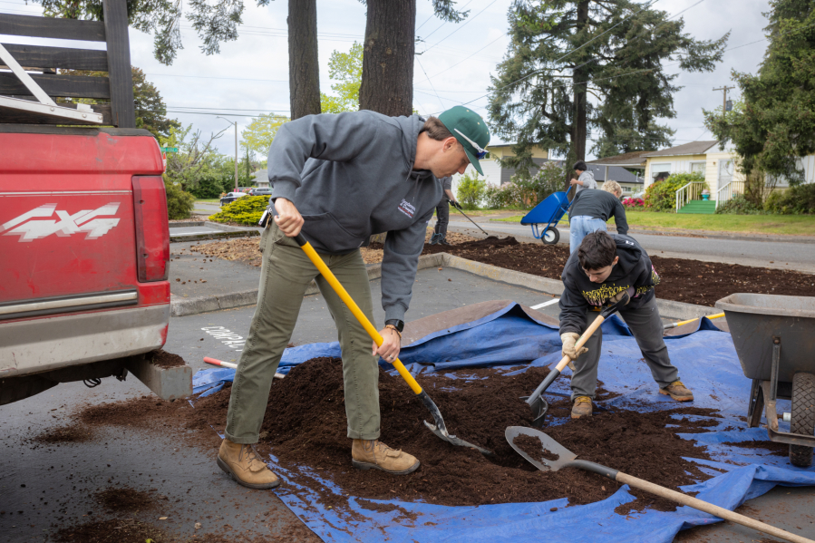 Josh Meyer, director of Mowtown Teen Lawn Care, and Alex Weeks, 16, shovel mulch into a wheelbarrow. The organization employs about 15 teens right now and expects to hire more going into summer. (Tommy Rhodes for The Columbian)