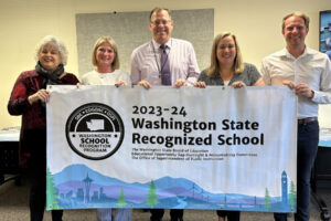 From left to right, Tracey MacLachlan, Sadie McKenzie, Superintendent Aaron Hansen, Wendy Morrill and Connor McCroskey hold a State Recognized School banner during a Washougal School Board meeting May 27. (Contributed by the Washougal School District)