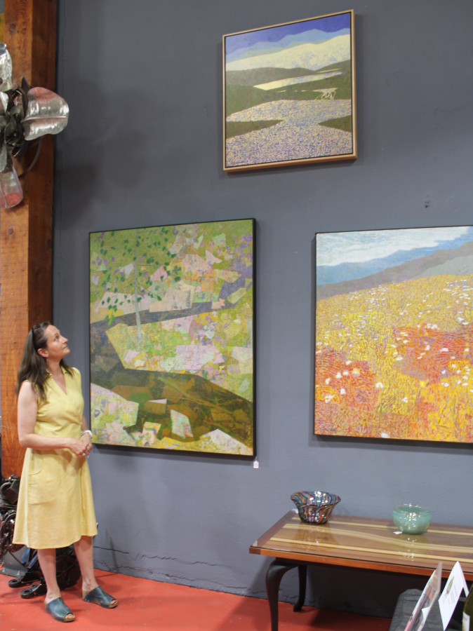 Maria Gonser, who co-owns Attic Gallery with her husband, Tommer Gonser, admires artwork by Michael Ferguson inside the downtown Camas art gallery on Friday. (Kelly Moyer/Post-Record)