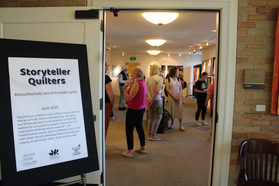 A crowd gathers inside the Second Story Gallery on the second floor of the Camas Public Library on Fridayfor the opening reception of the Storyteller Quilters’ art show, which runs through the month of June. (Kelly Moyer/Post-Record)