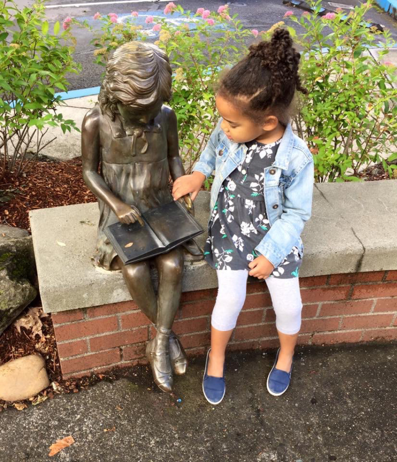 A young girl interacts with the Little Bronze Girl statue in downtown Camas in an undated photo. (Contributed by the Downtown Camas Association)