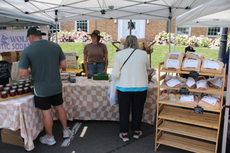 Camas Farmer's Market visitors peruse fresh-baked bread at the Washougal-based Sourdough Bakehouse booth on Wednesday afternoon, June 11, 2025.