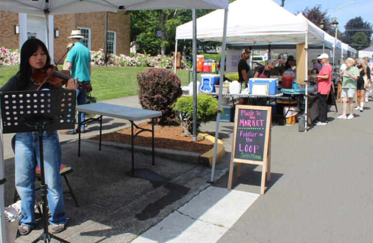 A musician plays outside the Camas Public Library in downtown Camas during the 18th annual Camas Farmer's Market on Wednesday, June 11, 2025.