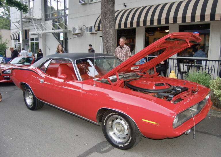 Visitors admire Jerry and Mary Sauer&rsquo;s 1970 Plymouth Cuda during the 2024 Camas Car Show. The classic red-on-red car later won the Best in Show trophy.