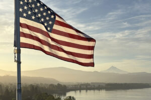 An American flag, perched on top of a tower crane at the Hyas Point construction site on the Washougal waterfront in June 2025, waves in the wind. (Courtesy of RKm Development)