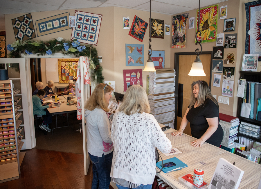 Owner Cheran Bee, from right, helps customers Bev Richardson and Diane Geisler of Puyallup on Friday at Fiddlesticks Quilt Shop in Vancouver. The quilt shop is one of the places sewers can go to get fabric and accessories now that Joann Fabric and Crafts has closed. (Taylor Balkom/The Columbian)