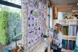 Diane Geisler of Puyallup looks at a quilt on the wall Friday at Fiddlesticks Quilt Shop in Vancouver. Geisler drove down to participate in the Western Washington Quilt Shop Hop. (Taylor Balkom/The Columbian)