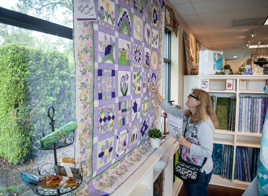 Diane Geisler of Puyallup looks at a quilt on the wall Friday at Fiddlesticks Quilt Shop in Vancouver. Geisler drove down to participate in the Western Washington Quilt Shop Hop. (Taylor Balkom/The Columbian)