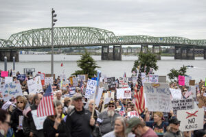 The Interstate 5 Bridge crosses the Columbia River behind a large crowd of protesters participating in the nationwide “No Kings” rally on Saturday on Waterfront Way at the Vancouver waterfront. (Photos by Taylor Balkom/The Columbian)