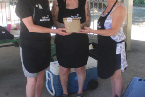 Refuel Washougal volunteers Anne Goforth, from left, Ann Stevens and Kerry O’Connor hold a sack lunch at Hathaway Park on July 25. (Photos by Doug Flanagan/Post-Record)