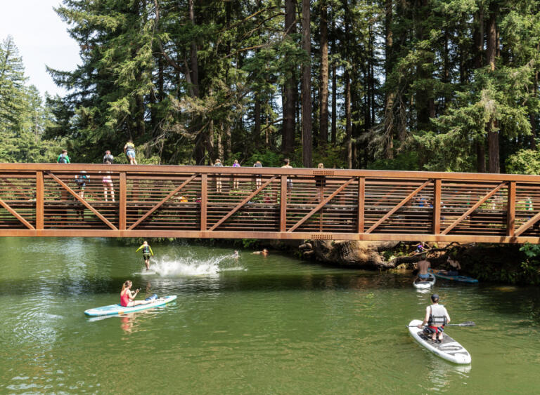 Paddleboarders wait as kids jump off a bridge into Round Lake on June 24 in Camas.