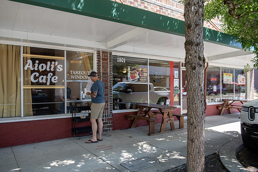 A potential customer pauses to check out the menu at Aioli’s Cafe in downtown Washougal on July 3. (Amanda Cowan/The Columbian)