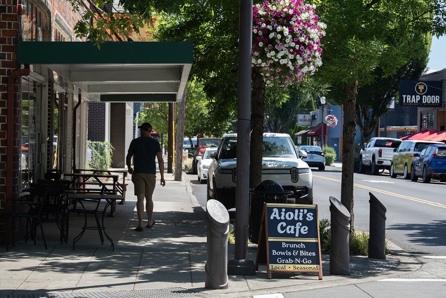 A pedestrian strolls past Aioli’s Cafe in downtown Washougal on July 3. (Amanda Cowan/The Columbian)