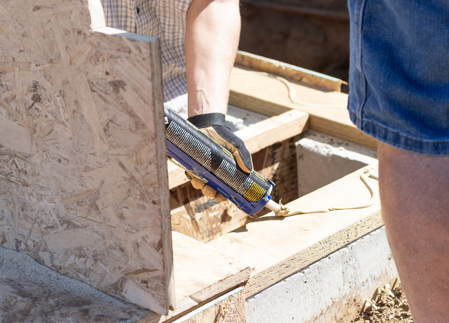Volunteer JP Milner applies adhesive Friday, July 11, 2025, in Washougal. The single-family, four-bedroom house is the first built in Washougal by Evergreen Habitat For Humanity. (Taylor Balkom/The Columbian)