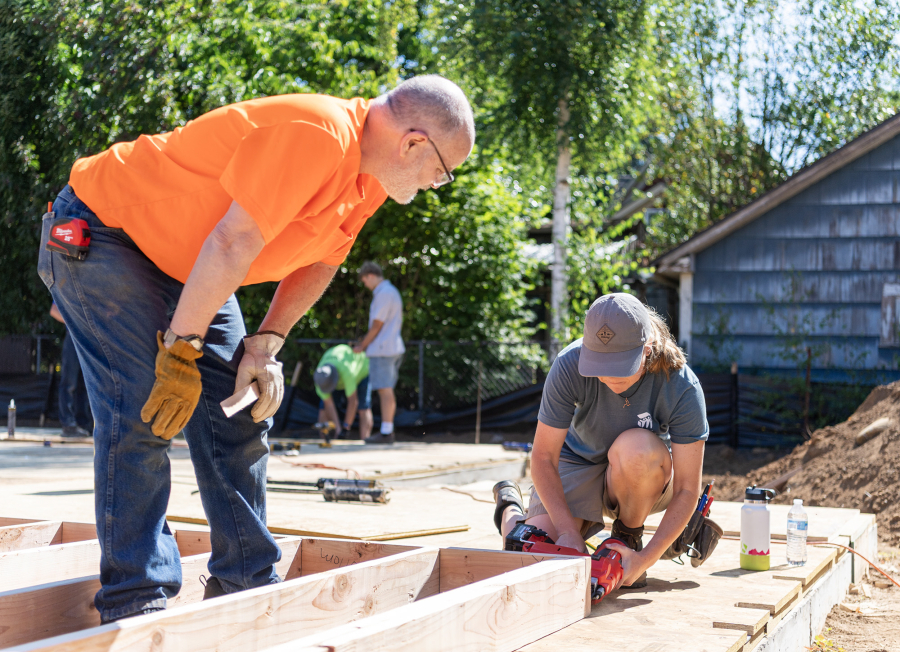 Volunteer Winfield Brackeen, left, watches as Ashley Madsen uses a nail gun Friday, July 11, 2025, in Washougal. The single-family, four-bedroom house is the first built in Washougal by Evergreen Habitat For Humanity. (Taylor Balkom/The Columbian)