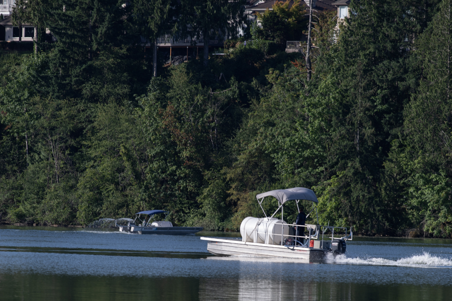 Crews from the city of Camas spray aluminum sulfate to the surface of Lacamas Lake on Tuesday morning. The chemical binds with phosphorus in the water, which the city hopes will reduce or eliminate the presence of toxic algae blooms. (Amanda Cowan/The Columbian)