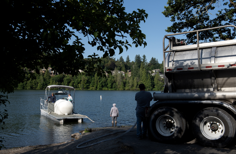 Boats come ashore for a refill at Lacamas Lake on Tuesday morning. Crews applied aluminum sulfate to the lake this week as the city works to control warm weather algae blooms. (Amanda Cowan/The Columbian)