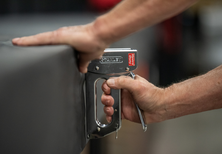 Cal Crawford uses a staple gun to prepare a table at the Canning and Dehydrating department of the Clark County Fair on Tuesday during setup for the fair at the Clark County Event Center at the Fairgrounds. (Taylor Balkom/The Columbian)