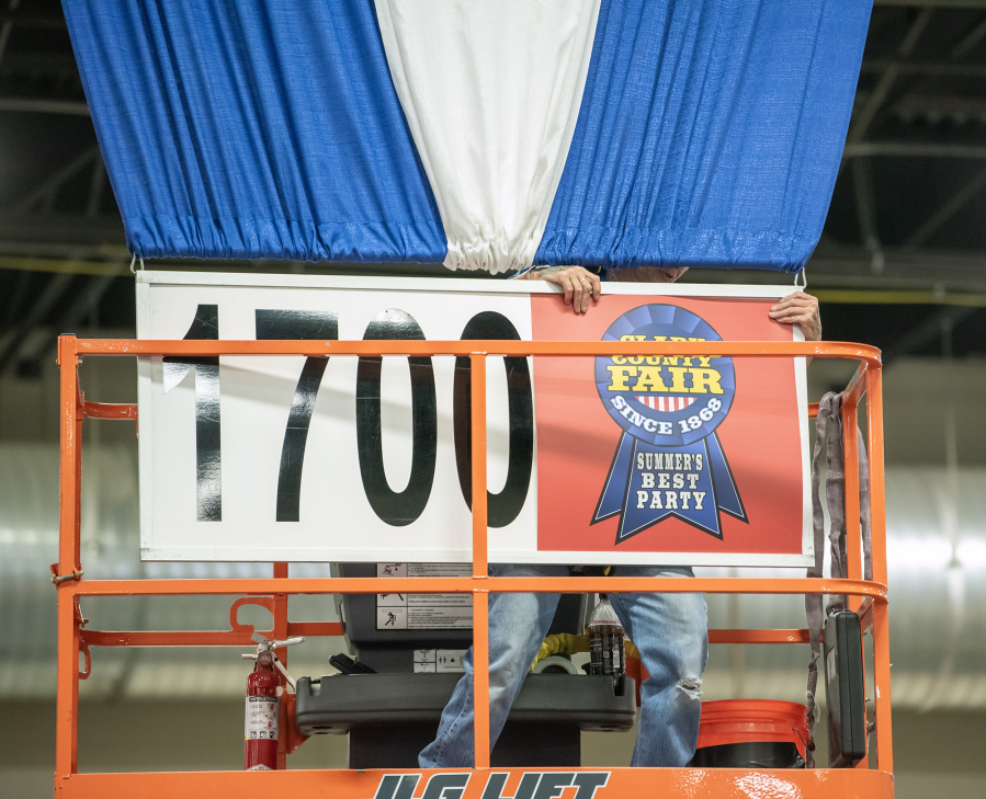 A worker hangs a sign Tuesday during setup for the Clark County Fair at the Clark County Event Center at the Fairgrounds.