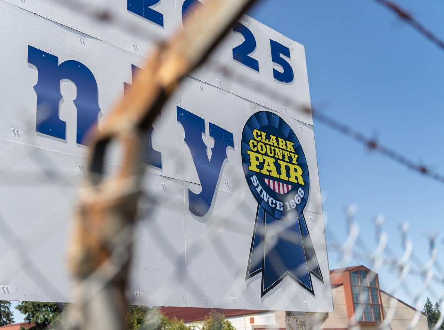 The sign for the Clark County Fair sits behind a fence surrounding the parking lot Tuesday during setup for the Clark County Fair at the Clark County Event Center at the Fairgrounds. (Taylor Balkom/The Columbian)