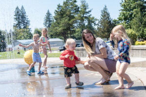 Kennedy Englund, 3, right, and her brother Bradley Englund, 1, center, laugh with mom on Tuesday at the Holley Park splash pad in La Center. “Splash pads are great water/cooling facilities for the community because, unlike the sandy or rocky shores of a river, pond or lake, the surface is accessible to wheelchair users and others with limited mobility,” said Kaley McLachlan-Burton, spokeswoman for Clark County Public Works.