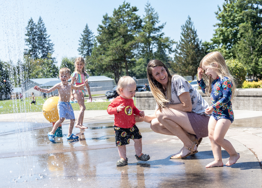 Kennedy Englund, 3, right, and her brother Bradley Englund, 1, center, laugh with mom on Tuesday at the Holley Park splash pad in La Center. “Splash pads are great water/cooling facilities for the community because, unlike the sandy or rocky shores of a river, pond or lake, the surface is accessible to wheelchair users and others with limited mobility,” said Kaley McLachlan-Burton, spokeswoman for Clark County Public Works.