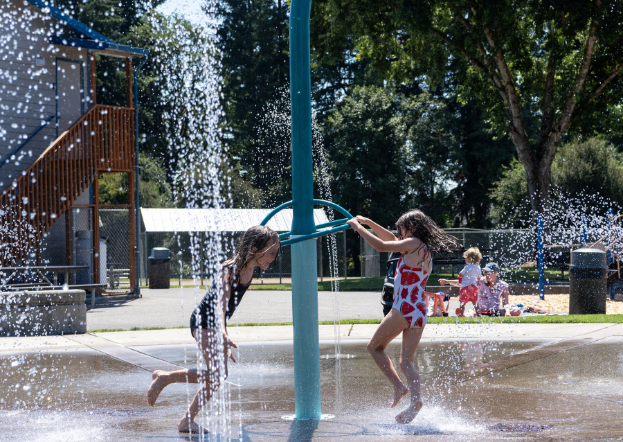 Emily, 8, left, and Alice Cash, 5, spin around a sprinkler structure Tuesday at the Holley Park splash pad in La Center. The splash pad was a compromise the city made when residents requested a water park. La Center’s Public Works and Community Development Director Tracy Coleman said a water park was unrealistic for the city’s size given the expense. (Taylor Balkom/The Columbian)