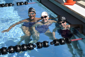 Christine McClafferty, left, poses with daughters Camille McClaffery, center, and Mavis McClafferty at the Mt. Hood Aquatic Center in Gresham, Ore. Inspired by their mother, Camille McClafferty, 19, and Mavis McClafferty, 9, have become successful competitive swimmers. (Micah Rice/The Columbian)