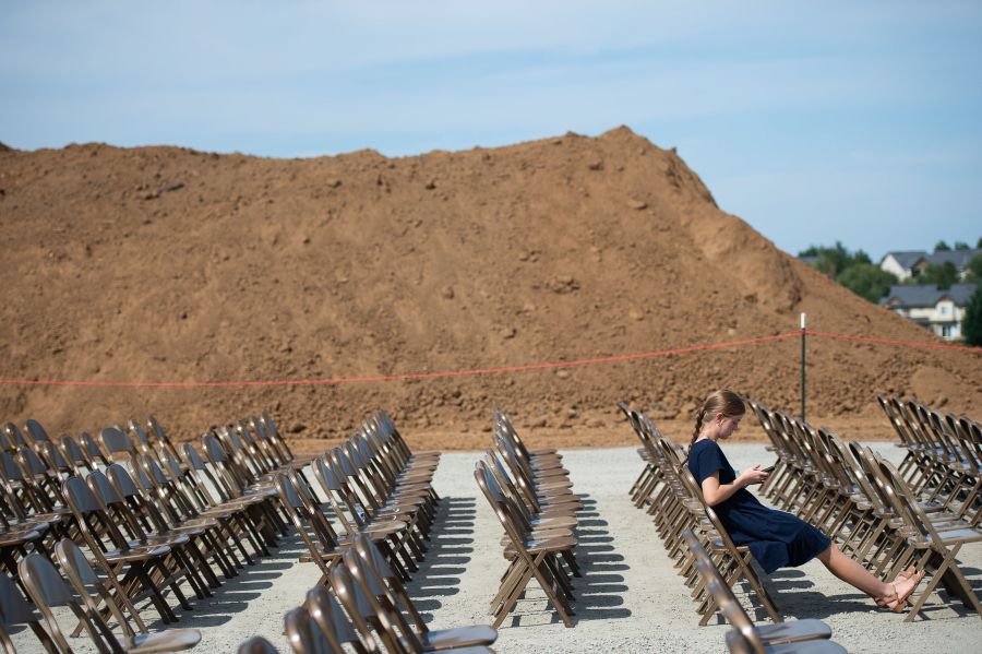 Sharon Clark, 15, of Vancouver, texts on her phone in front of a huge pile of soil after Saturday’s groundbreaking ceremony for the Vancouver Washington Temple.