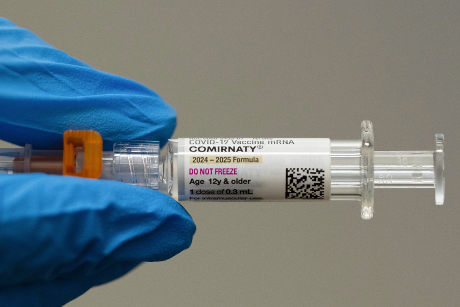 A pharmacist holds a Pfizer-BioNTech COVID-19 shot April 24 in Portland. Changing federal policies are creating confusion about vaccine availability and coverage. (Associated Press files)