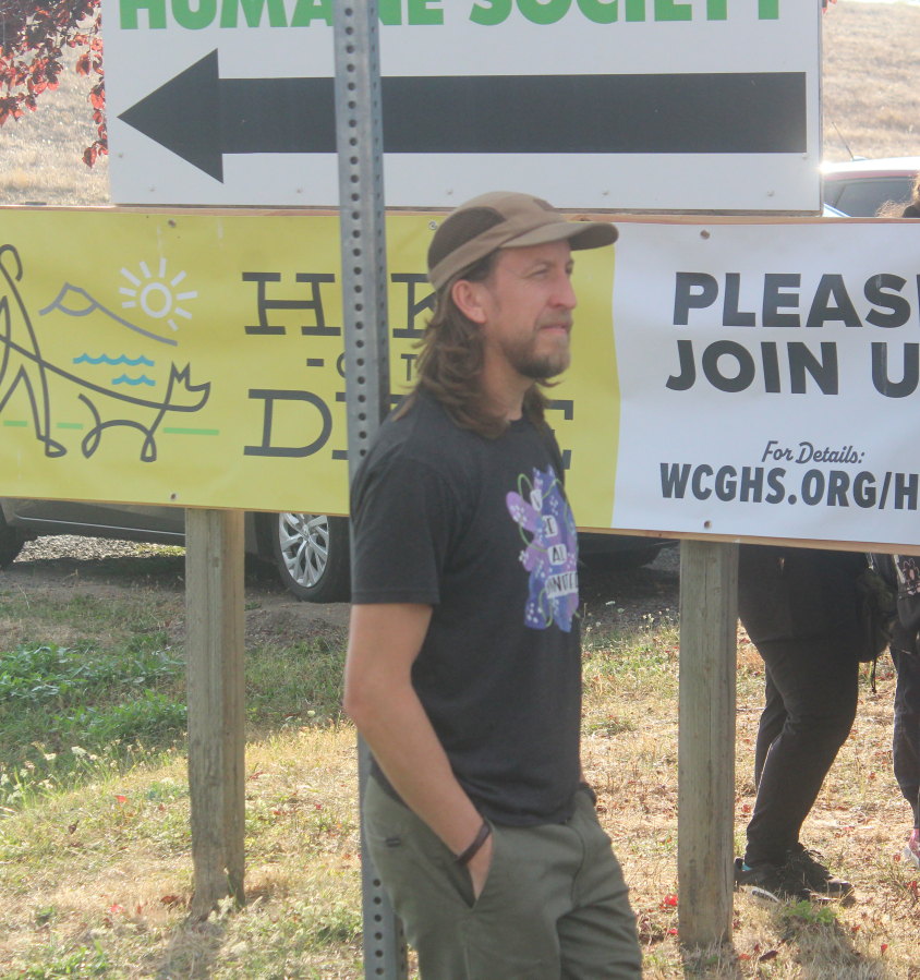 Washougal artist Travis London listens to a speech from West Columbia Gorge Humane Society Executive Director Micki Simeone during a dedication ceremony for the nonprofit’s new mural on Sept. 10. (Doug Flanagan/The Columbian)
