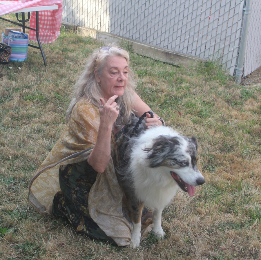 Sheila McCaig, a retired art teacher who assisted Travis London on a mural on the side of a Conex building at the West Columbia Gorge Humane Society, holds her dog Ozzie during a Sept. 10 dedication ceremony. (Doug Flanagan/The Columbian)