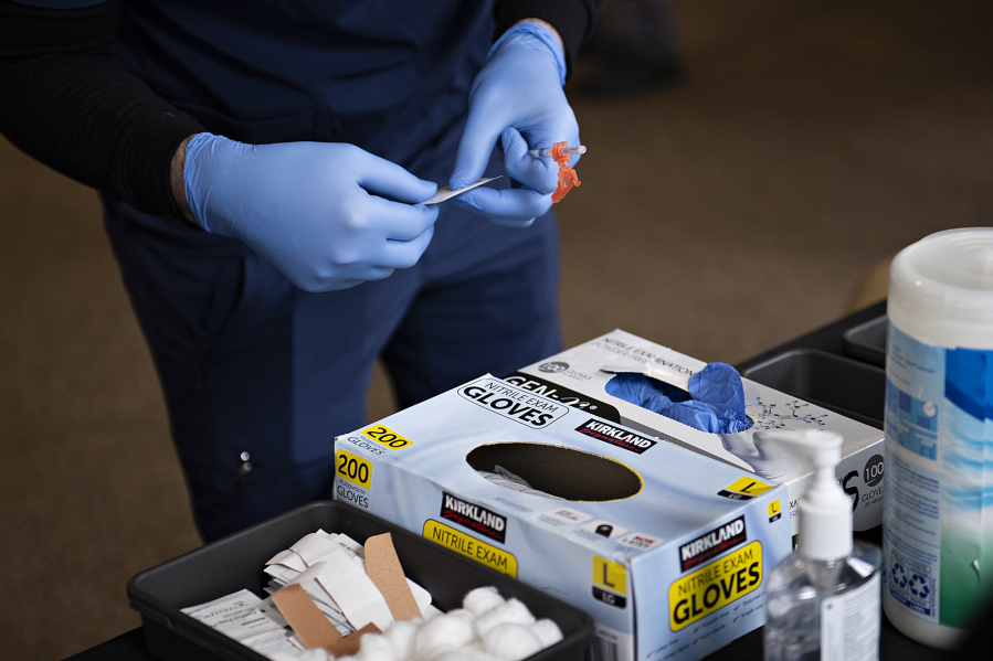 Jordan Bates of Aristo Healthcare prepares to administer a dose of COVID-19 vaccine Feb. 24, 2022. (Amanda Cowan/The Columbian files)