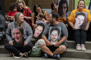 Participants in the Hands Across the Bridge event hold photos of themselves from before they became clean and sober. (Amanda Cowan/The Columbian)