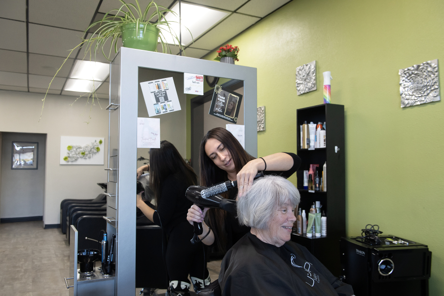 Overhead lights illuminate Jenifer Orsini of Utopia Salon, center, as she works with client Ruth Mougey of Vancouver on Tuesday. Utopia Salon is one of the local businesses that recently has used Clark Public Utilities&rsquo; incentives to install new lights to lower electricity use. (Amanda Cowan/The Columbian)