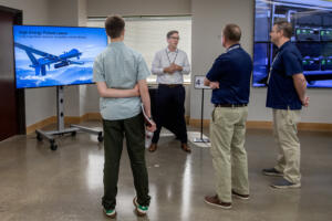 Kyle Osberg, senior engineering director, facing, chats with visitors at Camas-based nLIGHT on Monday morning. The company is celebrating 25 years in business.