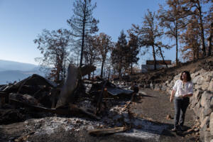 Landowner Megan Murphy walks past the remnants of her mobile home, left, which was destroyed in the Burdoin Fire. Two other structures on her property were treated and suffered only minor damage. DNR staff, local officials and others toured the Burdoin Fire area Sept. 24 to see how well treatment areas withstood the wildfire. (Amanda Cowan/The Columbian)