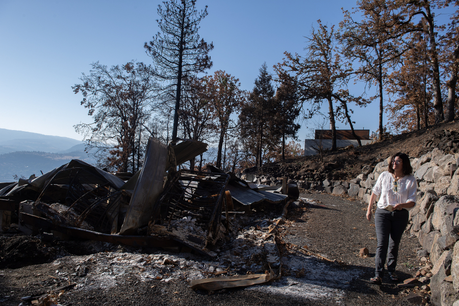 Landowner Megan Murphy walks past the remnants of her mobile home, left, which was destroyed in the Burdoin Fire. Two other structures on her property were treated and suffered only minor damage. DNR staff, local officials and others toured the Burdoin Fire area Sept. 24 to see how well treatment areas withstood the wildfire. (Amanda Cowan/The Columbian)