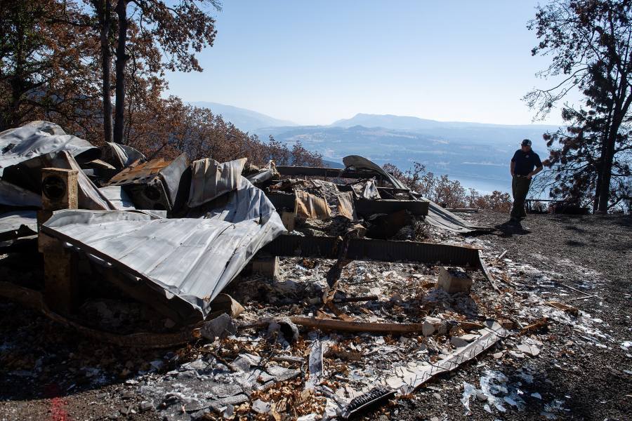 Tom Schoenfelder of the state Department of Natural Resources walks past the remnants of a mobile home that was destroyed in the Burdoin Fire near White Salmon. A nearby bunkhouse and outbuilding on the same property escaped the Burdoin Fire with only minor damage. (Amanda Cowan/The Columbian)
