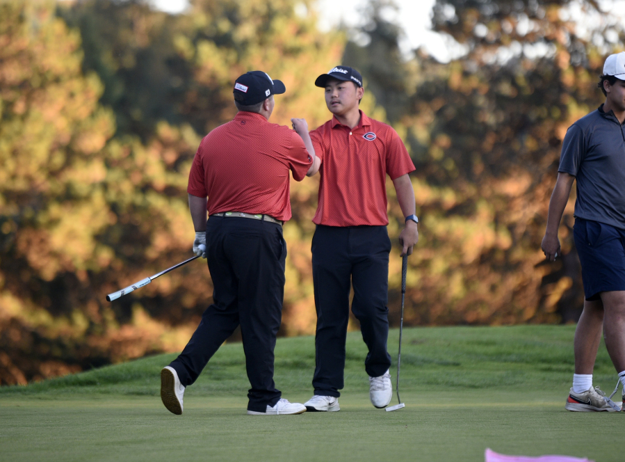 Ryker Jun, right, of Camas is congratulated by teammate Collin Clark after Jun beat Clark in a one-hole playoff at the Class 4A boys golf district tournament Tuesday at Lewis River Golf Course. (Tim Martinez/The Columbian)