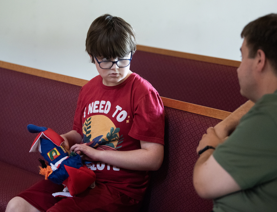 Lucas Hively, 11, looks over at his dad, David Hively, while playing with a toy Sept. 8 at Messiah Lutheran Church. Lucas and his mom, Robyn Kistemaker, have autism. When she gets upset, she shuts down. Kistemaker has shown Lucas what it is like for her when she gets overstimulated. Even though their reactions are opposite, they connected on a deeper level. (Photos by Taylor Balkom/The Columbian)