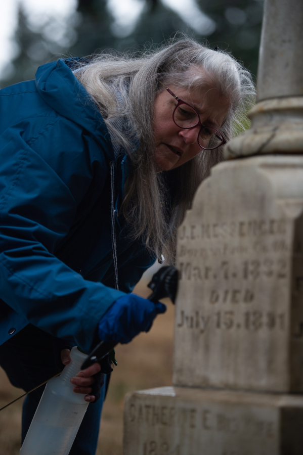 Julie Byler of Vancouver, a member of the Fort Vancouver chapter of the Daughters of the American Revolution&rsquo;s cemetery committee, scrubs the grave marker of the J.E. Messenger family at Brush Prairie Cemetery during a recent work party.