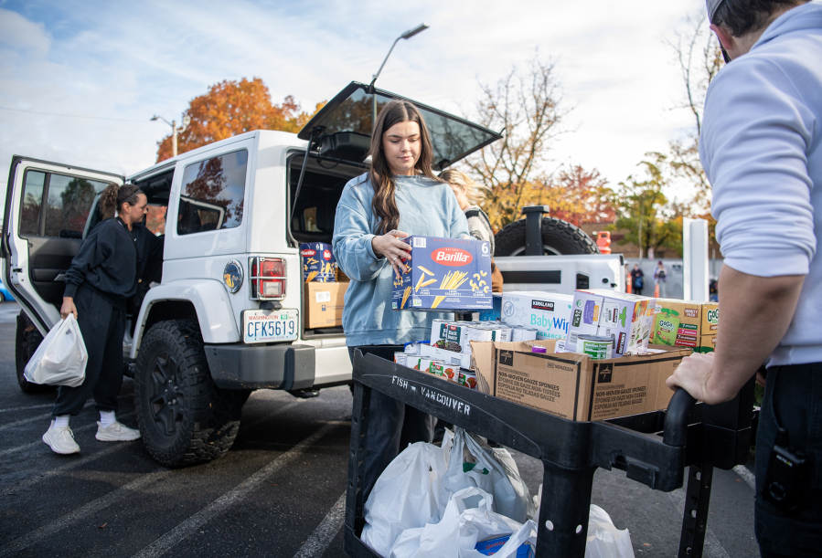 Margie Shepherd, center, loads donated food onto a cart Tuesday at FISH of Vancouver. (Taylor Balkom/The Columbian)